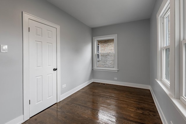 unfurnished room with dark hardwood / wood-style flooring and a healthy amount of sunlight