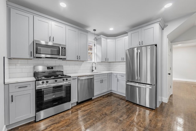 kitchen with pendant lighting, appliances with stainless steel finishes, dark hardwood / wood-style flooring, sink, and backsplash