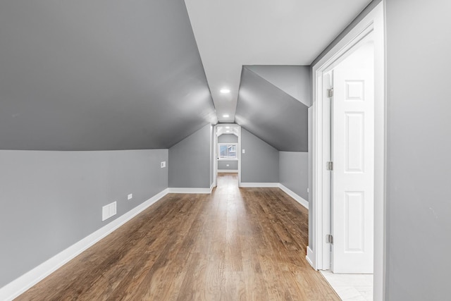 additional living space with light hardwood / wood-style flooring and vaulted ceiling