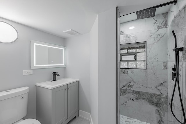 bathroom featuring vanity, toilet, and a tile shower