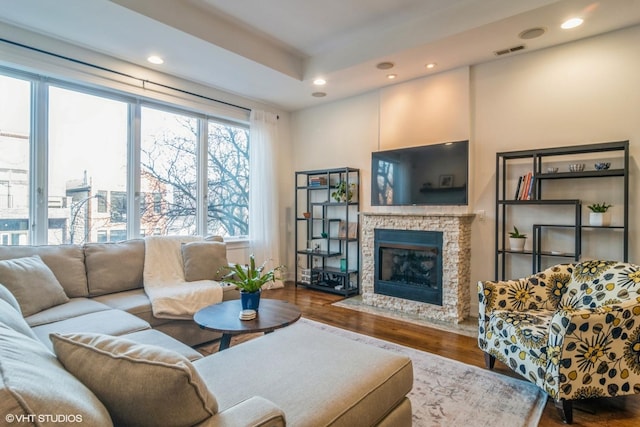 living room featuring hardwood / wood-style flooring and a stone fireplace