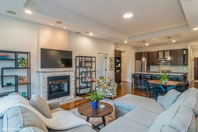 living room with a raised ceiling, dark hardwood / wood-style floors, and a fireplace