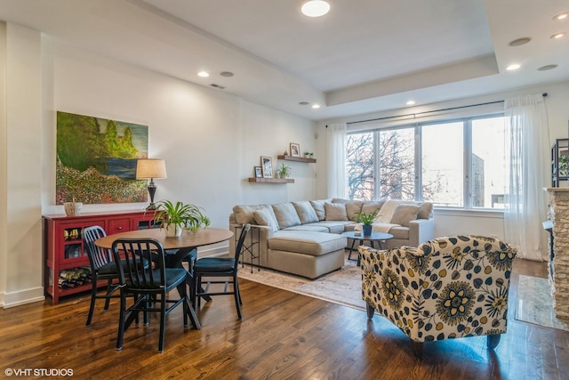 living room featuring a tray ceiling and dark hardwood / wood-style flooring