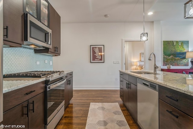 kitchen featuring sink, appliances with stainless steel finishes, hanging light fixtures, dark brown cabinetry, and decorative backsplash