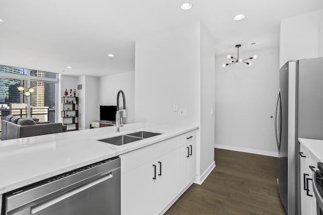 kitchen with sink, white cabinetry, appliances with stainless steel finishes, dark hardwood / wood-style flooring, and a notable chandelier