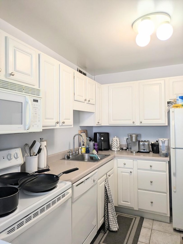 kitchen with white cabinets, white appliances, sink, and light tile patterned flooring