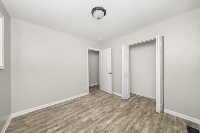 unfurnished bedroom featuring a closet and hardwood / wood-style flooring