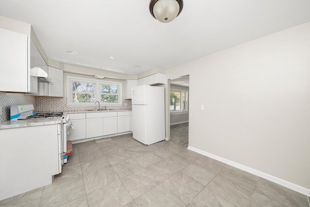 kitchen featuring sink, white appliances, white cabinets, and a healthy amount of sunlight