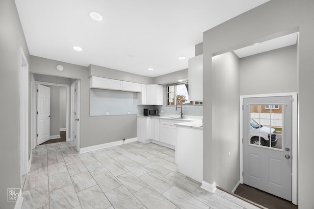 kitchen featuring sink, backsplash, white cabinetry, and a wealth of natural light