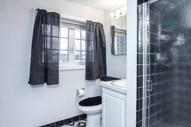 bathroom featuring toilet, a textured ceiling, a shower with shower door, and vanity