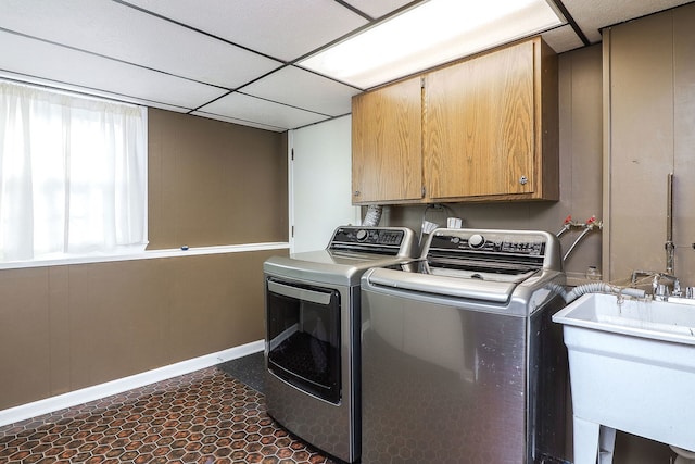 laundry room featuring sink, washer and clothes dryer, cabinets, and dark tile patterned flooring