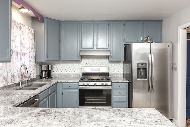 kitchen with appliances with stainless steel finishes, sink, tasteful backsplash, gray cabinetry, and light stone countertops