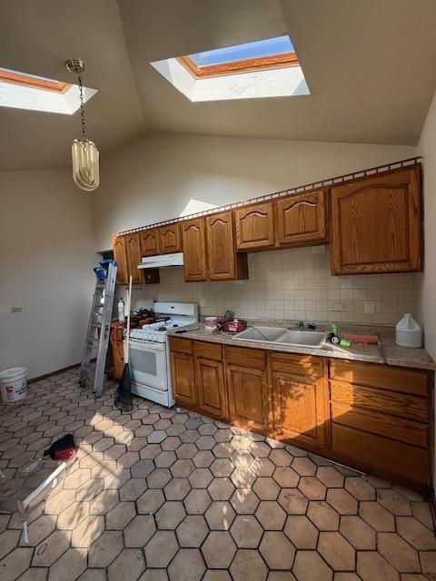 kitchen with hanging light fixtures, white range with gas cooktop, decorative backsplash, vaulted ceiling with skylight, and sink