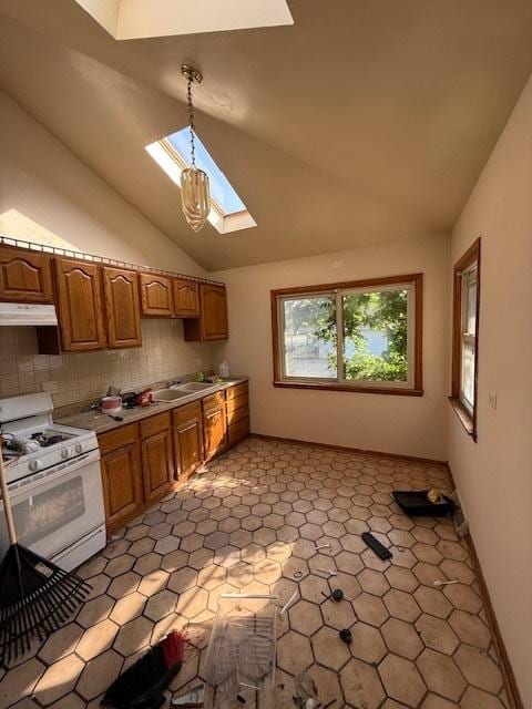 kitchen with white gas range oven, hanging light fixtures, vaulted ceiling with skylight, sink, and backsplash