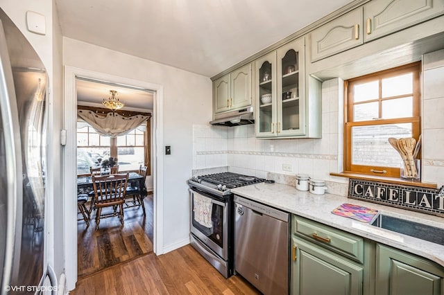 kitchen with light stone countertops, sink, dark hardwood / wood-style flooring, backsplash, and stainless steel appliances