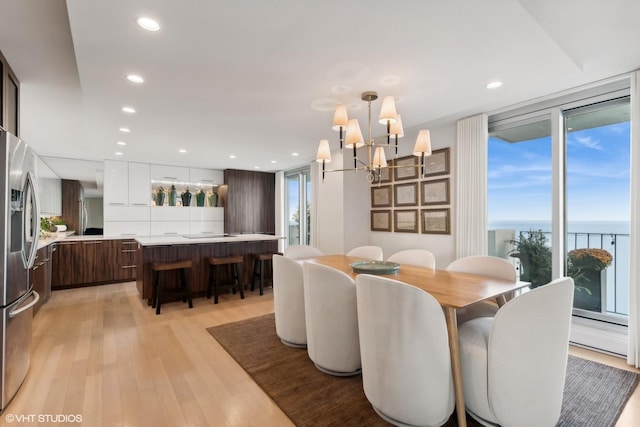 dining room with a water view, plenty of natural light, an inviting chandelier, and light hardwood / wood-style floors