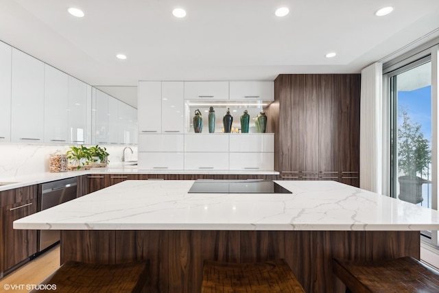 kitchen with white cabinetry, black electric stovetop, a kitchen bar, and decorative backsplash