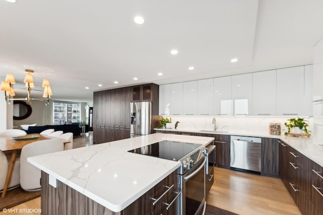 kitchen featuring sink, stainless steel appliances, light stone counters, dark brown cabinetry, and white cabinets