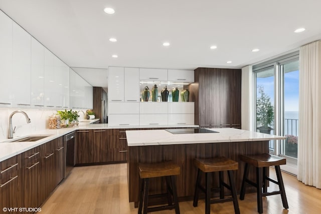 kitchen with sink, a kitchen island, white cabinets, and a kitchen bar