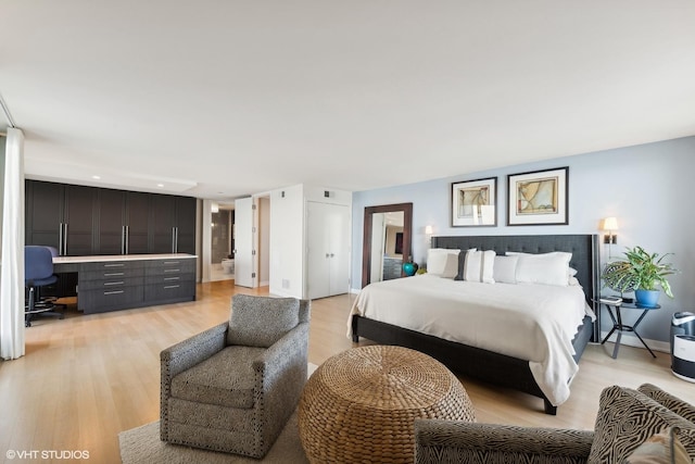 bedroom with built in desk, light hardwood / wood-style floors, and ensuite bathroom