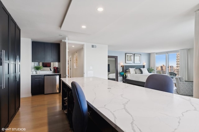 kitchen with light hardwood / wood-style flooring, light stone countertops, and dishwasher