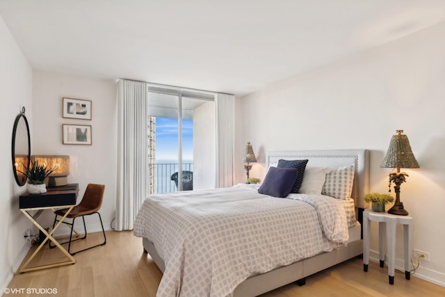 bedroom with floor to ceiling windows, access to outside, and light hardwood / wood-style flooring