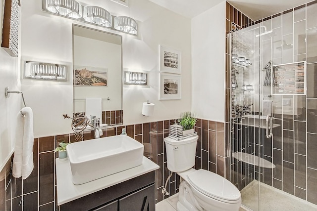 bathroom featuring a shower with door, vanity, tile walls, and toilet