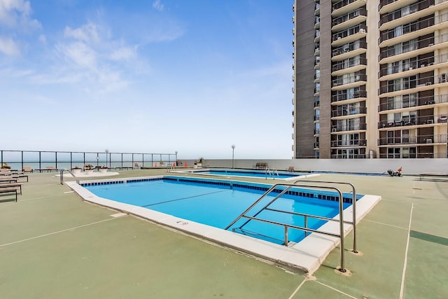 view of swimming pool with a water view and a patio area