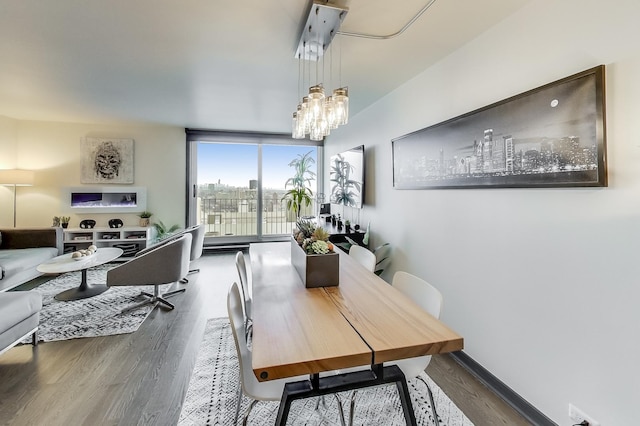 dining space featuring hardwood / wood-style flooring, a chandelier, and a wall of windows