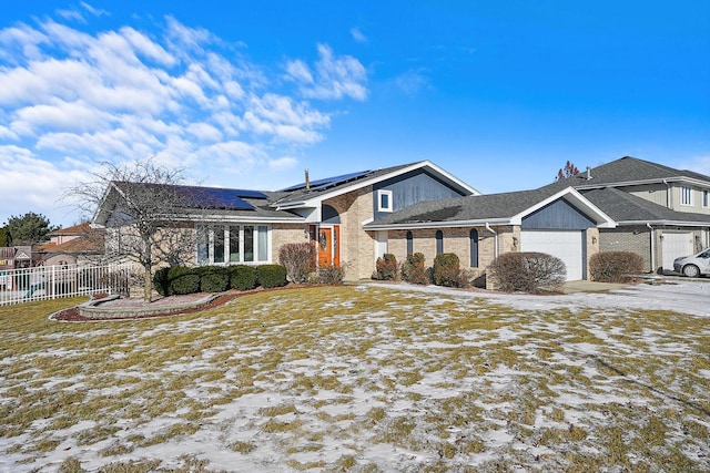 single story home with a garage, a lawn, and solar panels