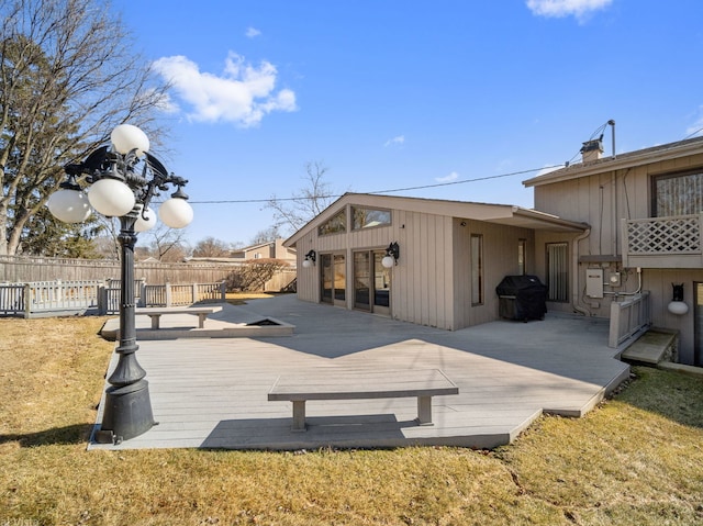 wooden terrace featuring a lawn, grilling area, and fence