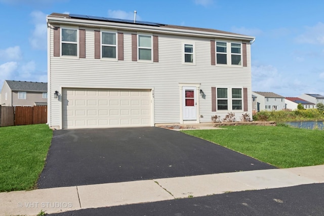 view of front of home featuring a garage, a front lawn, and solar panels