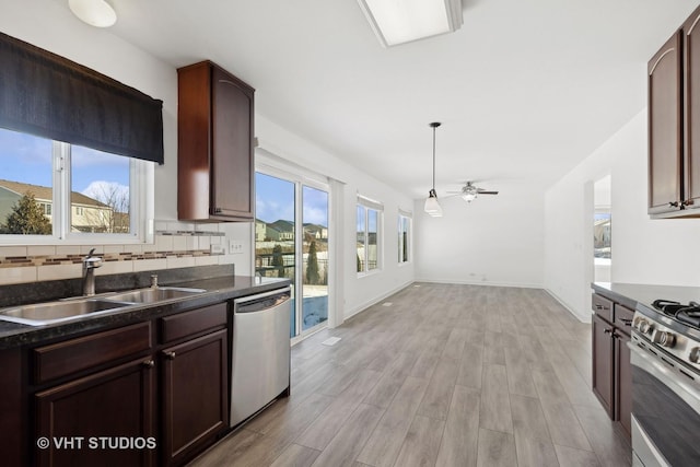 kitchen with sink, hanging light fixtures, ceiling fan, stainless steel appliances, and light hardwood / wood-style flooring