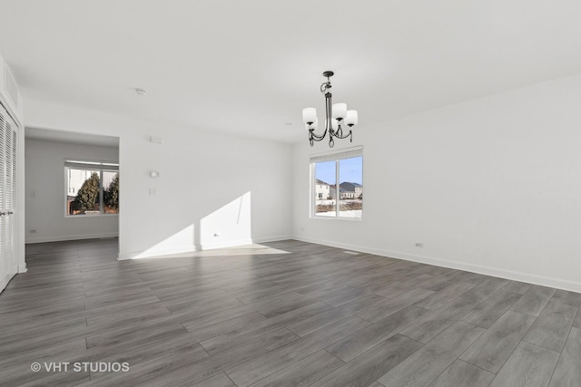 empty room with dark hardwood / wood-style floors and a chandelier