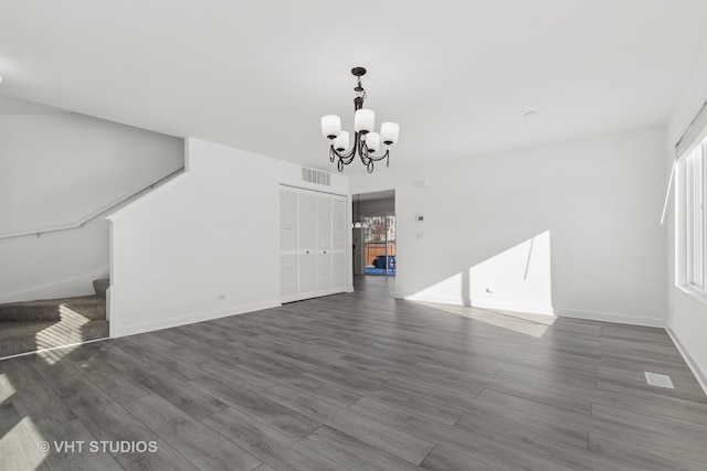 unfurnished living room featuring a notable chandelier and dark wood-type flooring