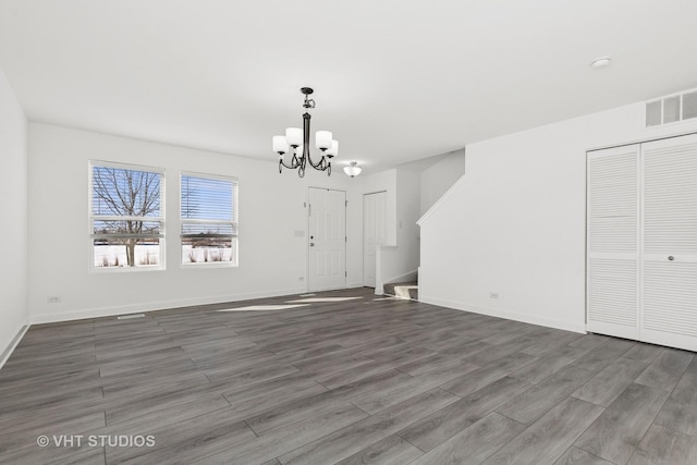 unfurnished dining area with a notable chandelier and dark hardwood / wood-style flooring