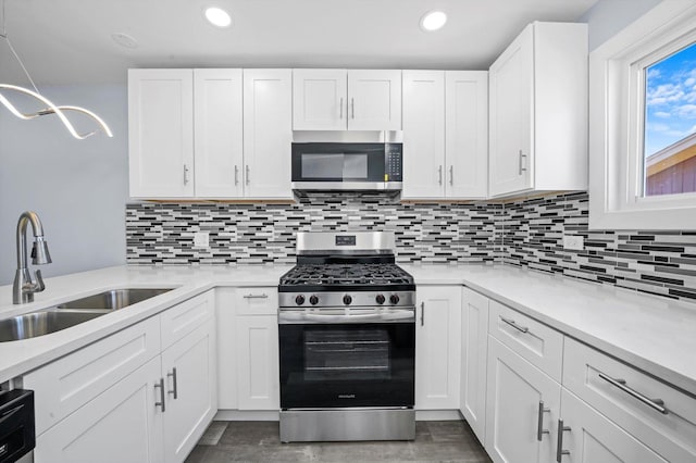 kitchen with tasteful backsplash, appliances with stainless steel finishes, sink, and white cabinets