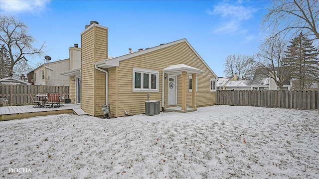 snow covered rear of property with central AC unit and a deck