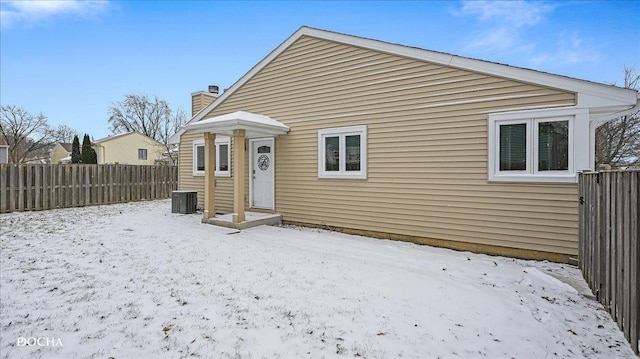 snow covered rear of property with central air condition unit