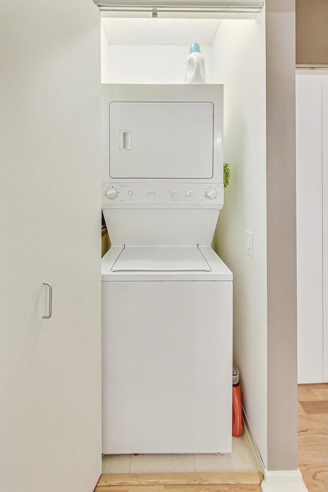 clothes washing area with stacked washing maching and dryer