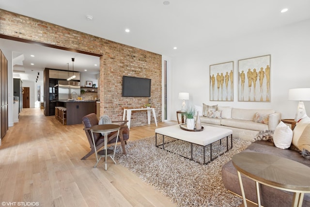 living room with brick wall and light hardwood / wood-style flooring