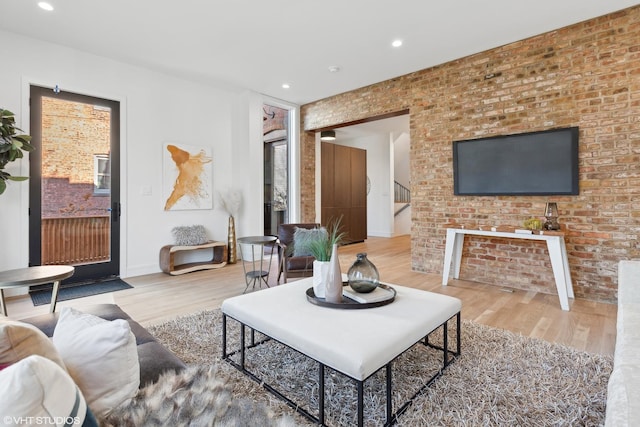 living room featuring hardwood / wood-style flooring and brick wall