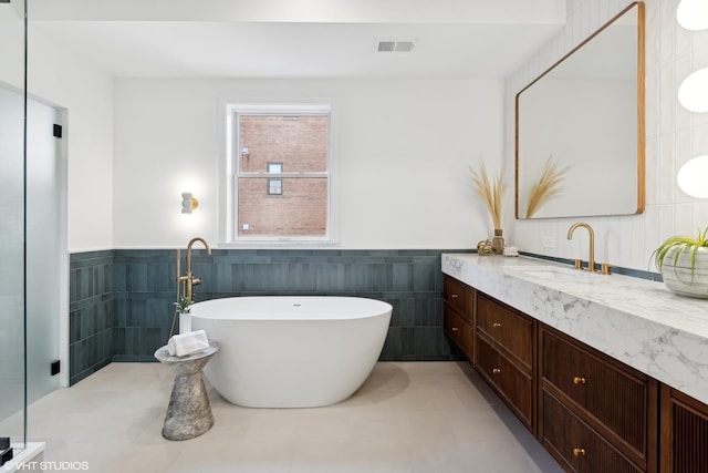 bathroom with a bathing tub, tile patterned flooring, vanity, and tile walls