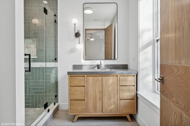 bathroom featuring a shower with door and vanity