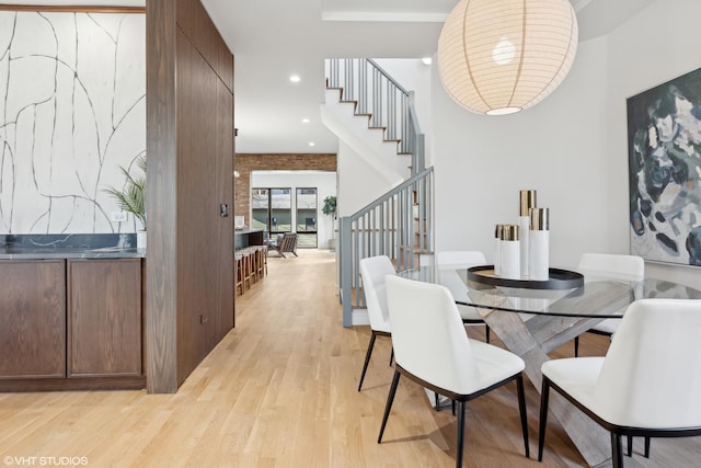 dining space featuring light wood-type flooring and brick wall