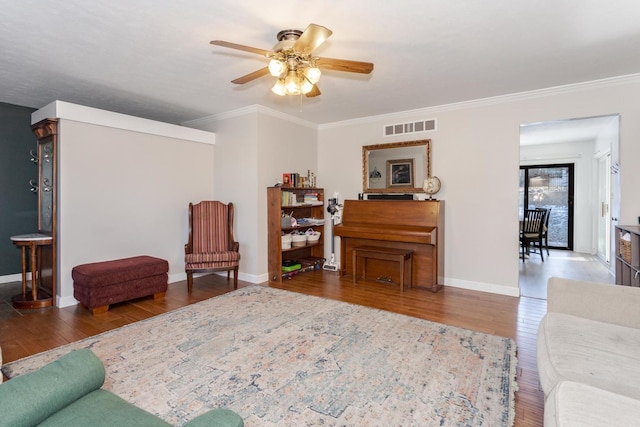 living room with wood-type flooring, ornamental molding, and ceiling fan