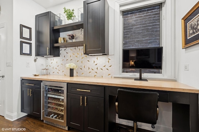 bar featuring butcher block counters, tasteful backsplash, built in desk, dark hardwood / wood-style flooring, and beverage cooler