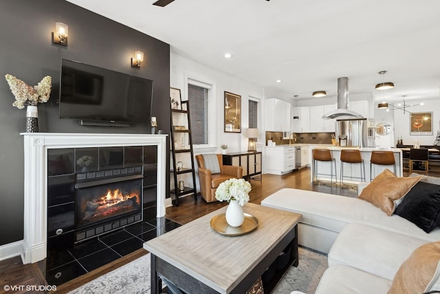 living room featuring a tiled fireplace, dark hardwood / wood-style floors, and ceiling fan