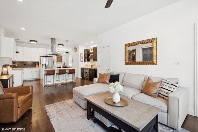 living room featuring dark wood-type flooring, sink, and ceiling fan