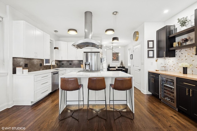 kitchen with sink, beverage cooler, island exhaust hood, a center island, and stainless steel appliances